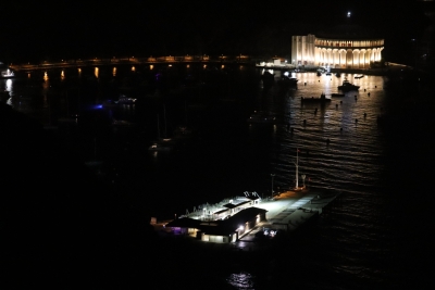 Nighttime view of Avalon Harbor with the illuminated Catalina Casino glowing across the water, boats anchored in the dark bay.